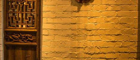 A brick wall with a wooden door and two wall-mounted decorative items.