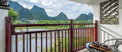 A balcony with a view of mountains, a table with shoes and a tray, and a decorative wall panel.