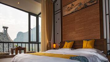 A bedroom with a large window, a bed with white bedding, and a wooden headboard.