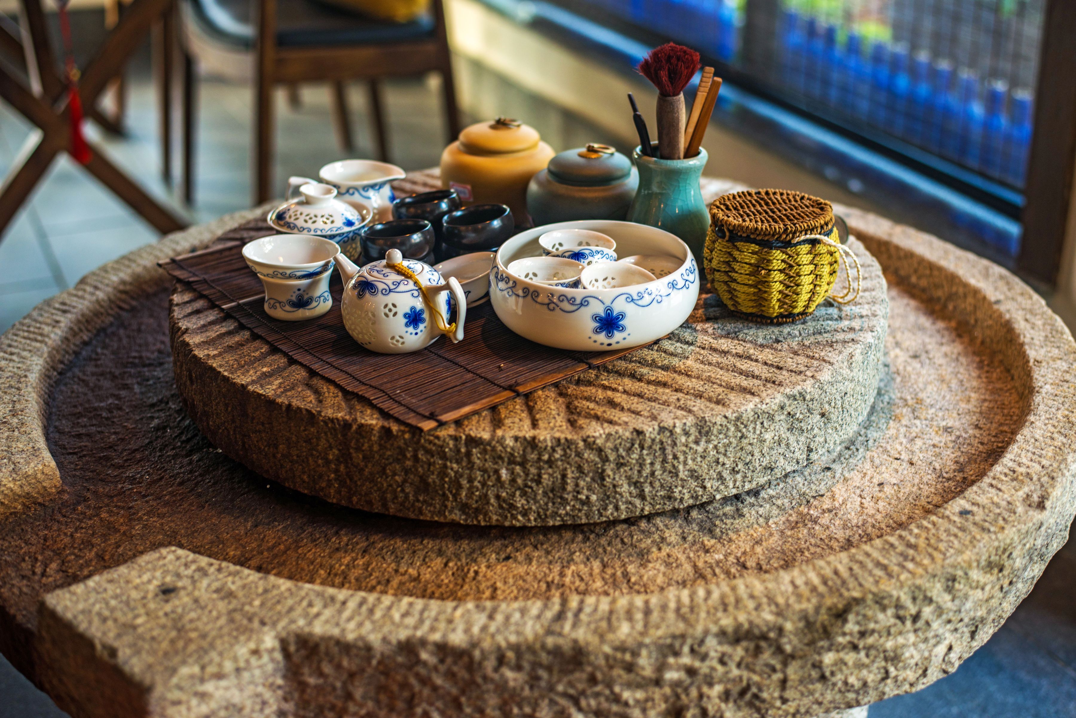A stone table with various ceramic tea sets and a woven basket.