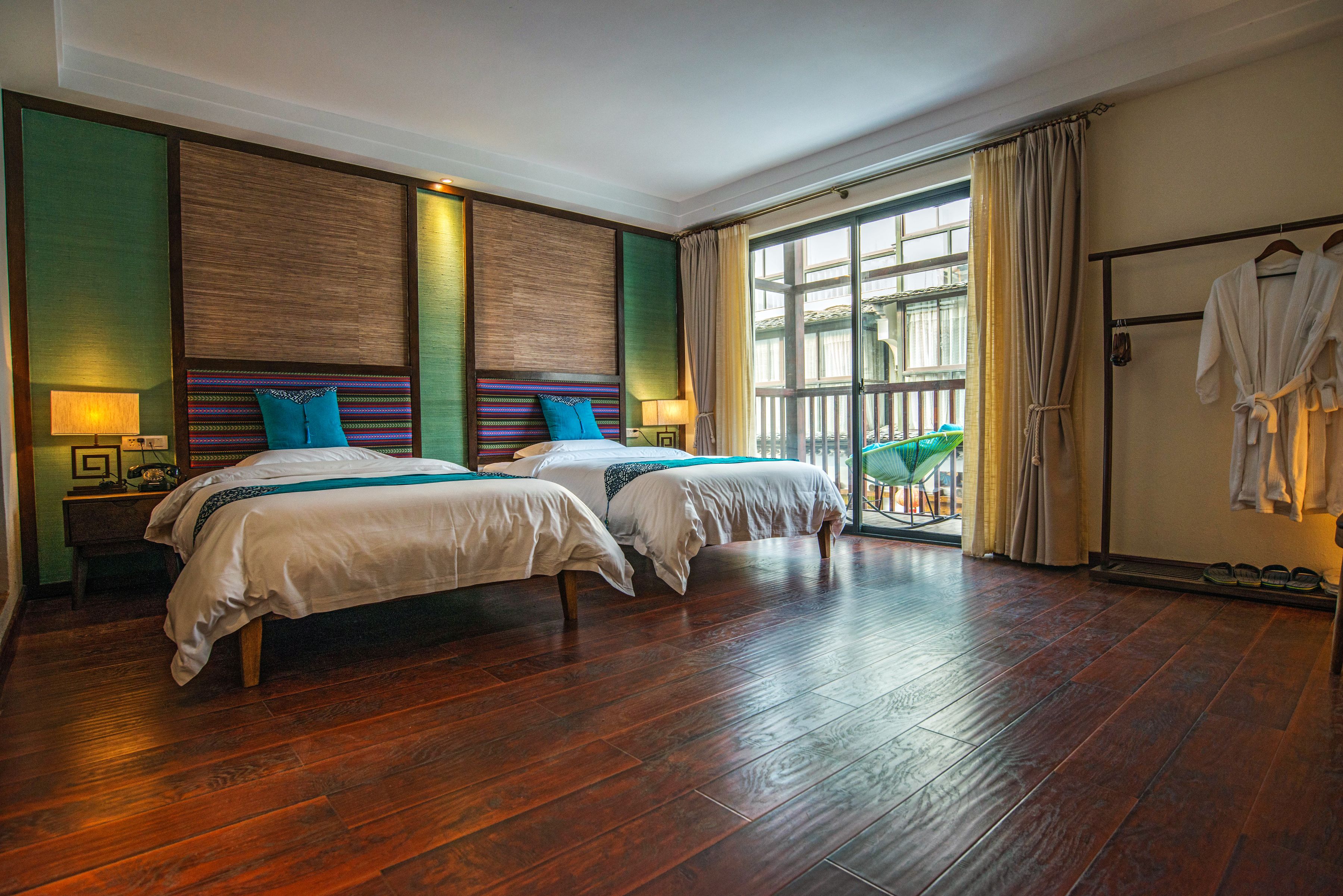 Une chambre d’hôtel avec deux lits, un plancher en bois et un balcon avec vue.