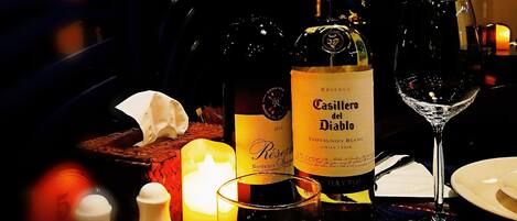 A table with wine bottles, glasses, and a candle.