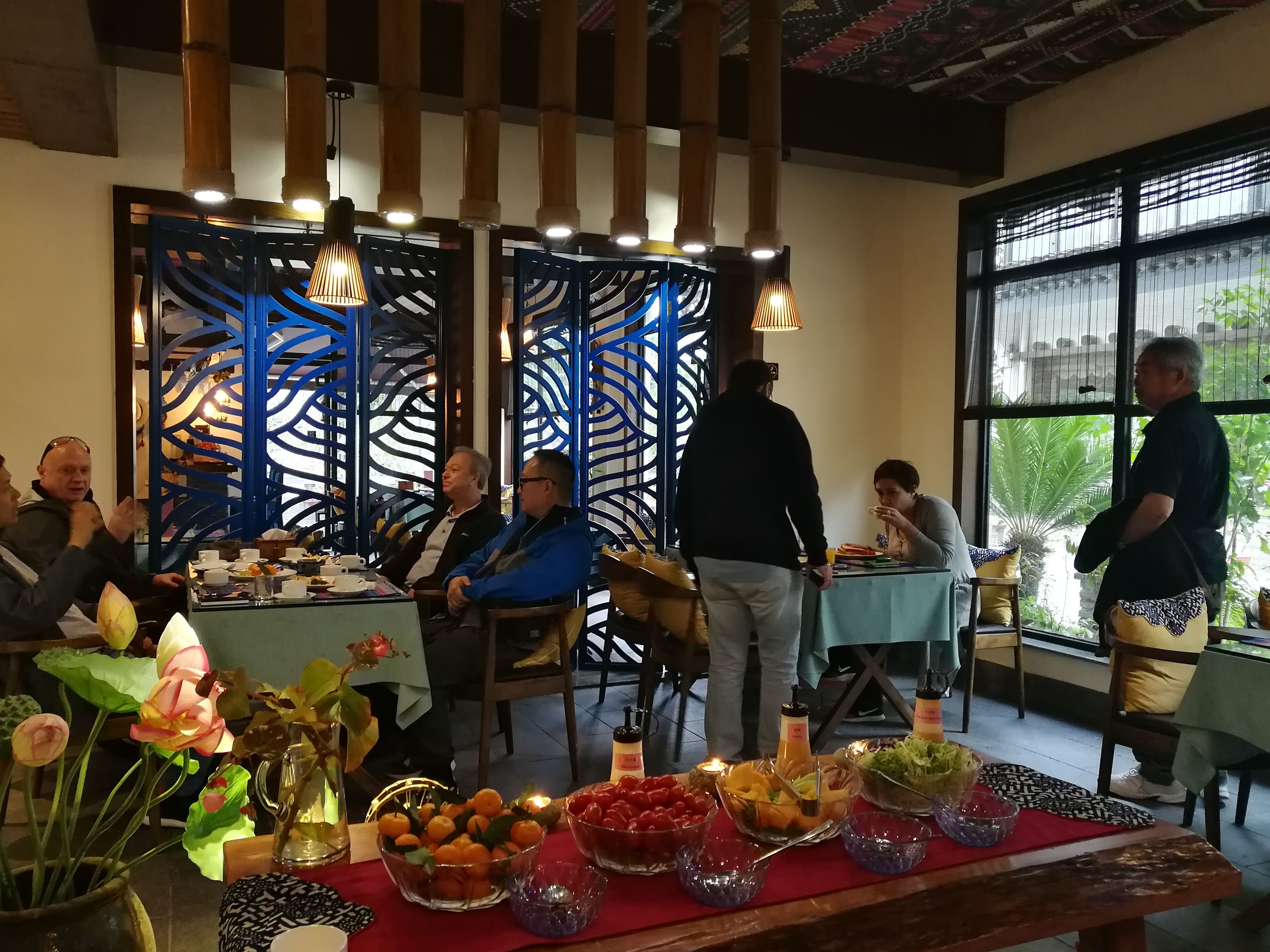Un espace repas avec des tables dressées pour le service, des éléments décoratifs et une vue dégagée grâce à de grandes fenêtres.
