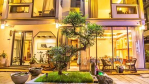 A building with a well-maintained garden featuring a bonsai tree, outdoor seating, and a visible entrance. - Secret Courtyard Resort Hotel (Guilin)