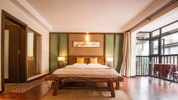A hotel room with a large bed, wooden headboard, and a view of the outside through large windows.