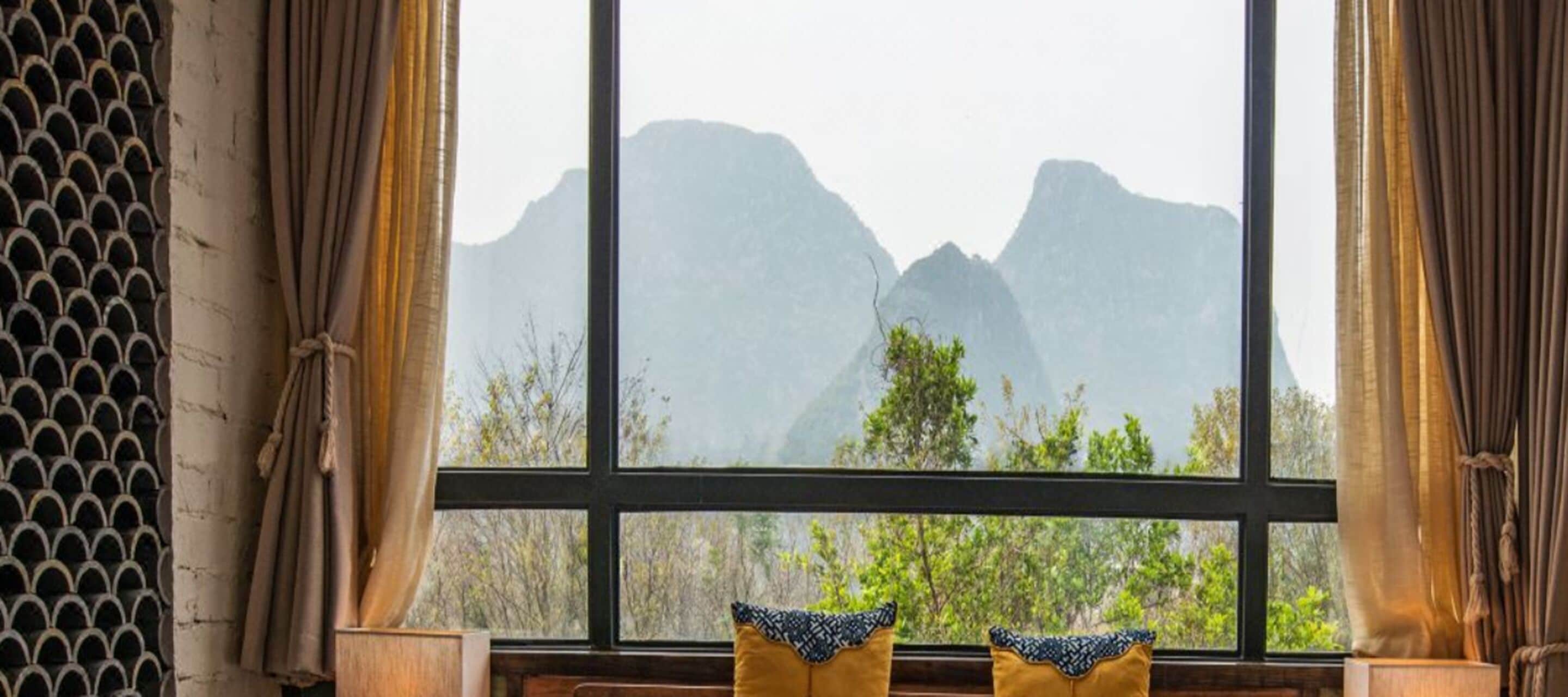 Una habitación con un ventanal, cortinas y dos almohadas.