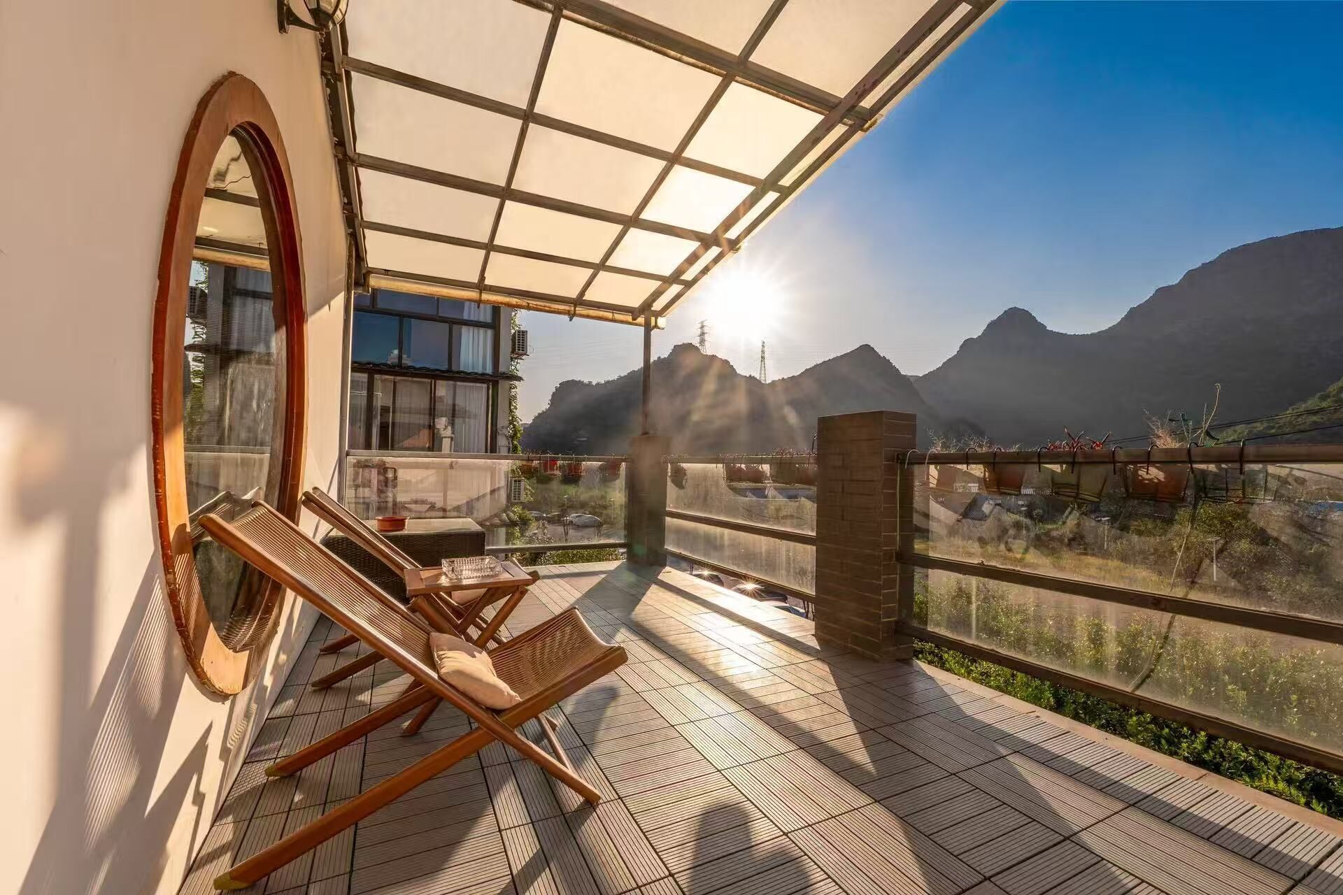 Un balcón con vistas a montañas, una silla de madera y una mesa.