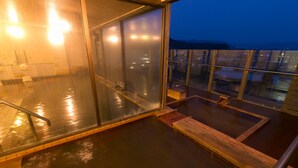 A glass-enclosed hot tub area with a view of the city at dusk. - Aso Hotel (Aso)