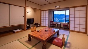 A traditional Japanese room with tatami flooring, a wooden table, and a television. - Aso Hotel (Aso)