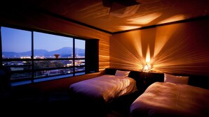 A hotel room with two beds, a large window with a view of mountains and city lights, and a unique ceiling design. - Aso Hotel (Aso)