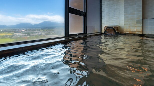 A hot spring room with a view of distant mountains and a tiled wall. - Aso Hotel (Aso)