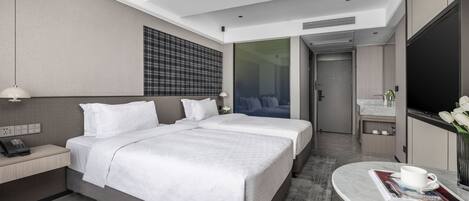 A modern hotel room with a large bed, a desk, a bathroom, and a TV.