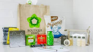 A variety of travel items including a bag labeled 'Boutique Stays', organic chips, Twinings' tea, and toiletries.