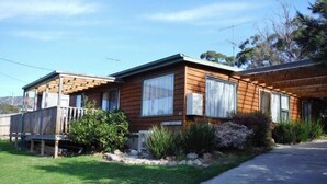 Una casa de madera de dos pisos con un porche cubierto y un letrero que dice "CAMP AS COTTAGE".