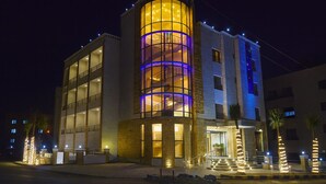 A modern hotel with a prominent cylindrical tower featuring a spiral staircase, large windows, and a well-lit entrance. - Al Jamal Hotel (Amman)