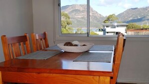 Mesa de jantar com um prato de biscoitos, dois jogos americanos e quatro cadeiras de madeira.
