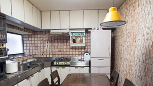 Eine Küche mit Holztisch und -stühlen, einem Herd, einer Mikrowelle und einem Kühlschrank.