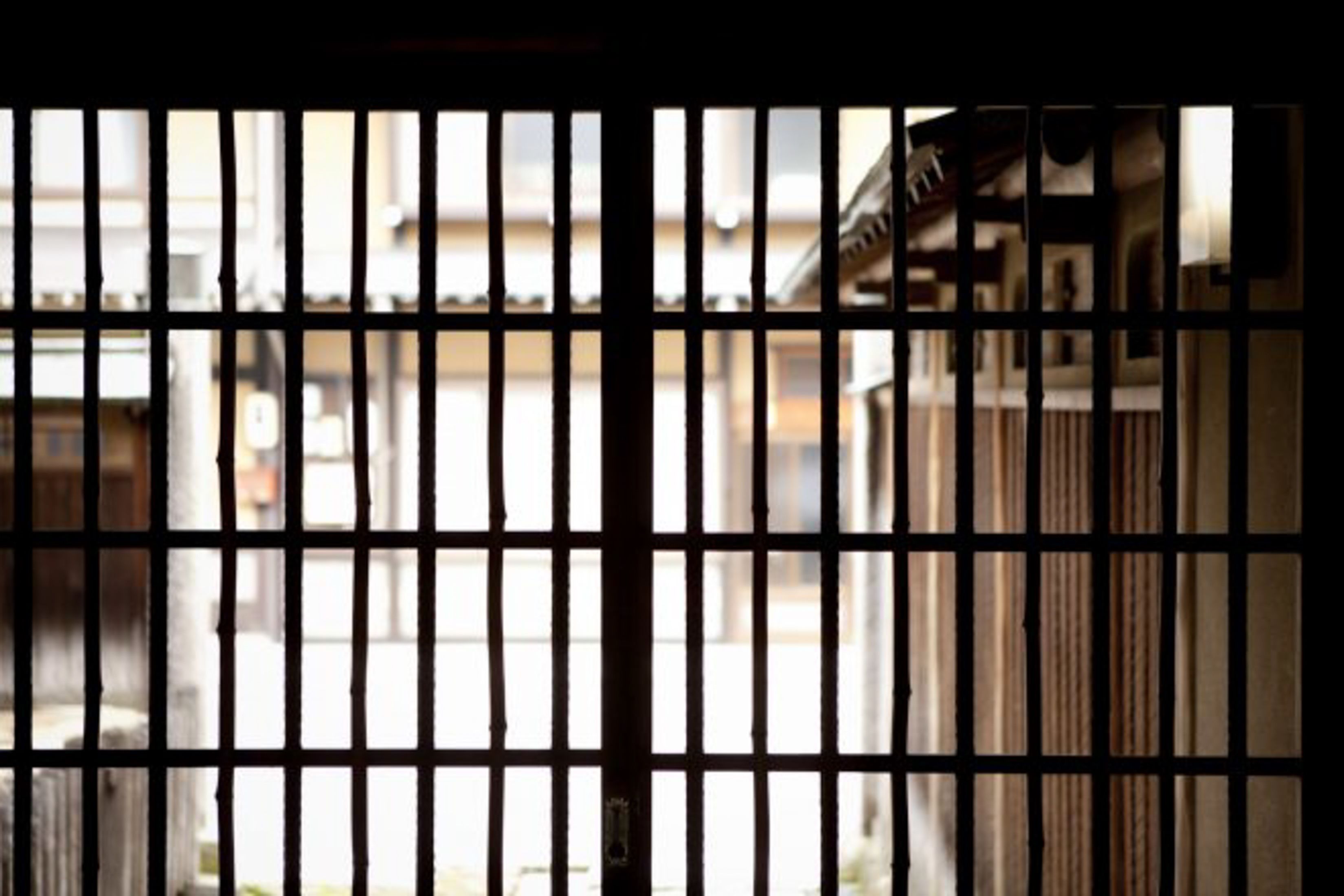 A barred window with a view of buildings in the background.