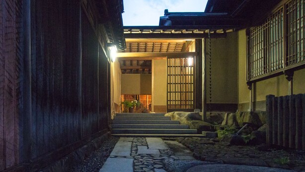 Ein traditionelles japanisches Gebäude mit einem Kiesweg, der zu einer Holztür führt.