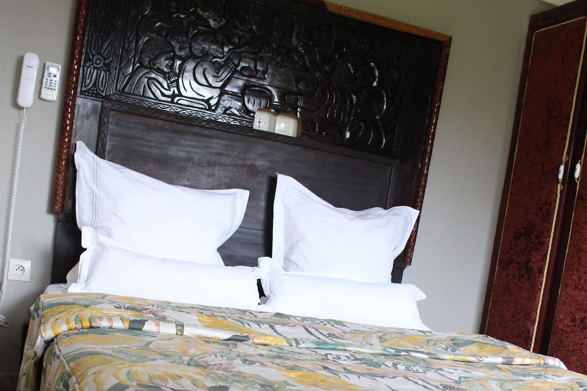 A bed with a floral bedspread, a wooden headboard, and white pillows.