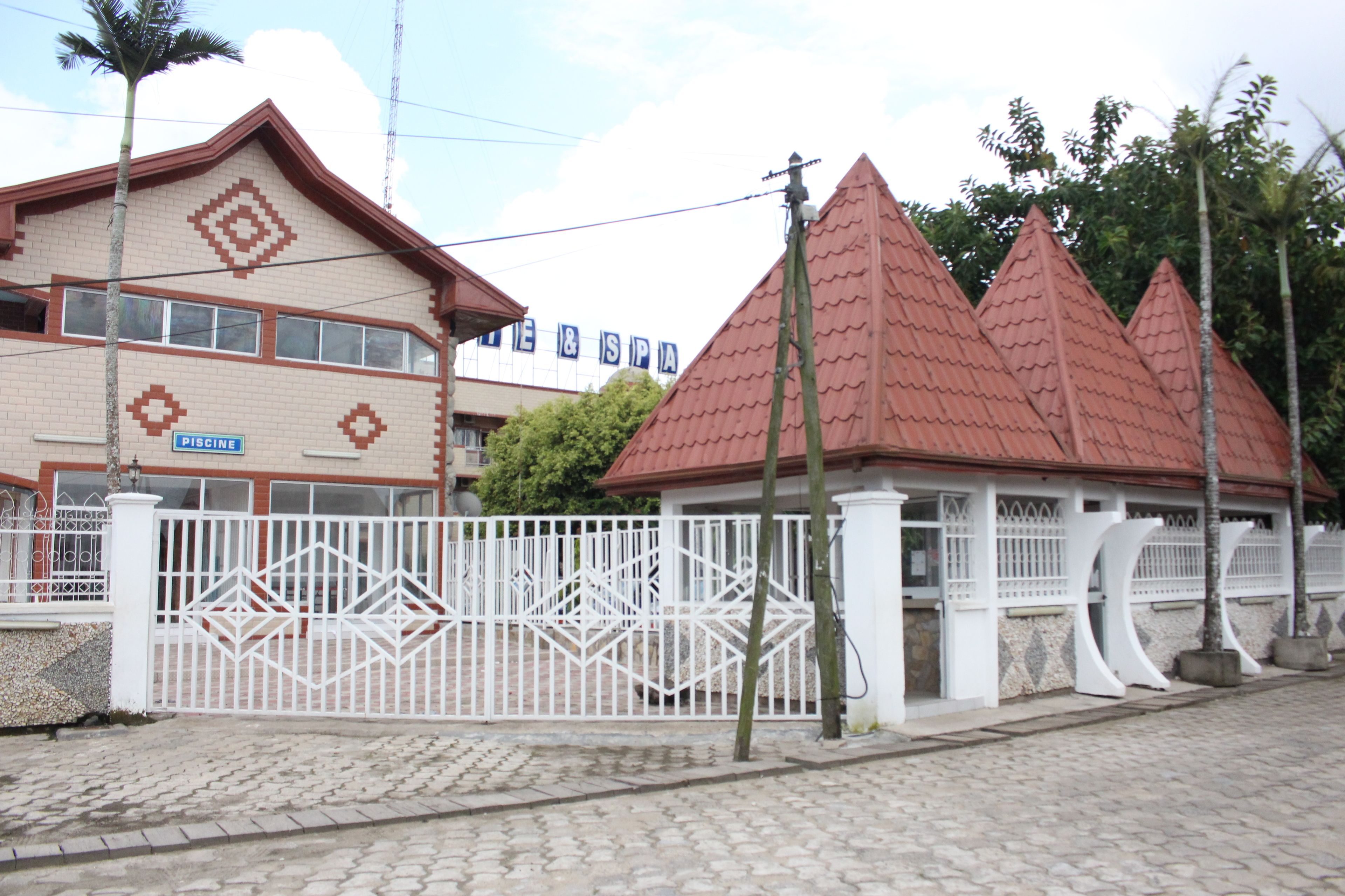 A building with a sign reading "PISCINE" and a separate structure with a red roof.