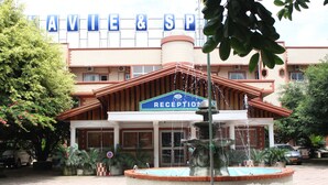 A hotel reception with a fountain in the center, surrounded by potted plants. - Hôtel Belavie (Bonaberi)