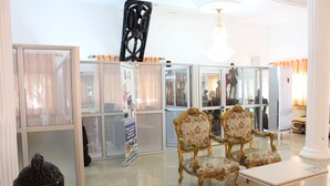 A spacious lobby with a high ceiling, a chandelier, and a seating area with ornate chairs. - Hôtel Belavie (Bonaberi)