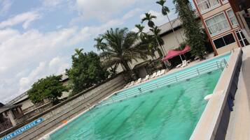 Relax by the pool surrounded by palm trees and lounge chairs.