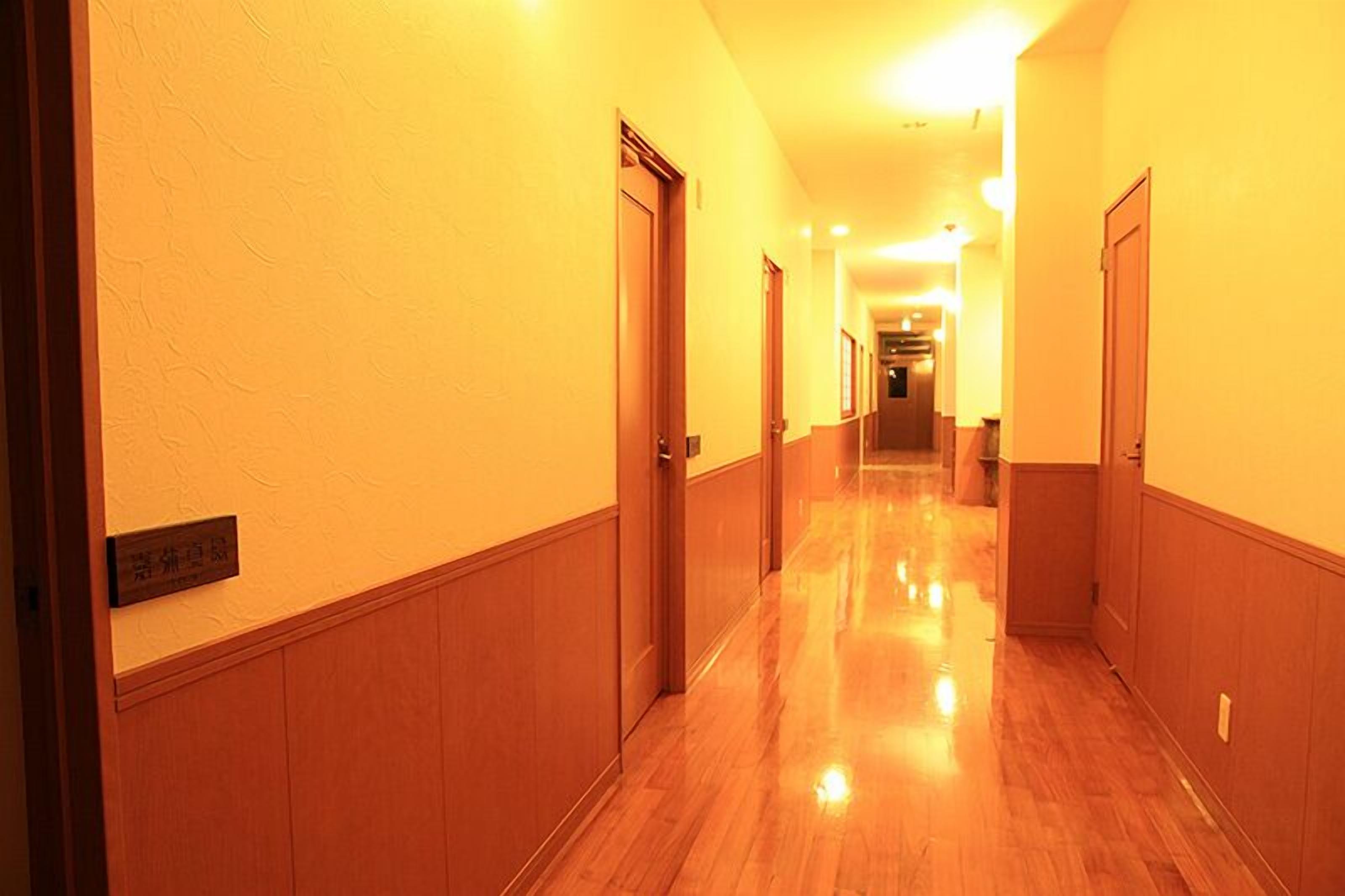 A hotel corridor with wooden paneling, a polished floor, and doors on both sides.