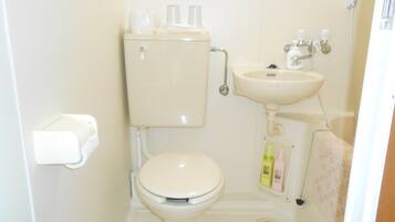 A small, white bathroom with a toilet, sink, and a toilet paper holder.