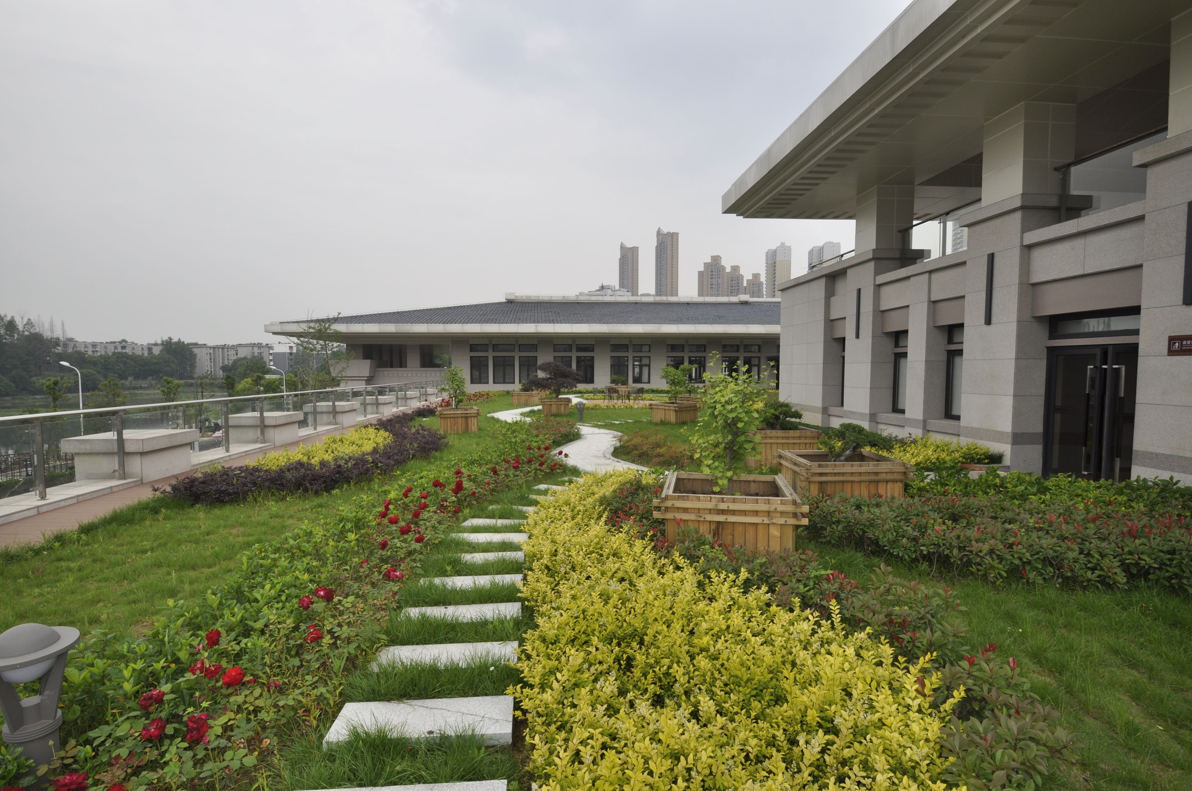 Un bâtiment moderne doté d’un jardin avec des allées, des bancs et une variété de plantes.