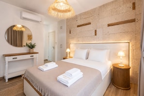A neatly made bed with folded towels, a round mirror, a bedside lamp, and a wooden nightstand. - Alacati Limonaia Hotel (Cesme)