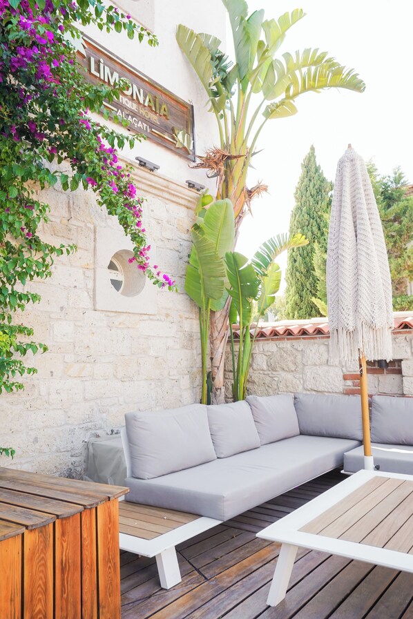 A patio area with a white sofa, wooden tables, and a sign for 'Limonada'. - Alacati Limonaia Hotel (Cesme)