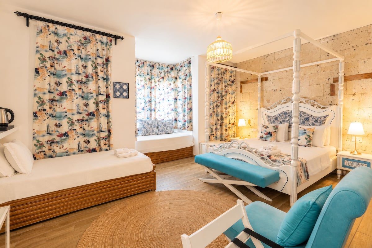 A bedroom with a four-poster bed, a sofa bed, a daybed, and a chair.