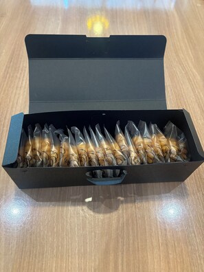 A black box with a handle, containing several items wrapped in clear plastic.