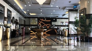 Un hall d’entrée spacieux, doté d’un sol en marbre poli, d’un grand lustre et d’une décoration moderne, notamment une œuvre d’art centrale.