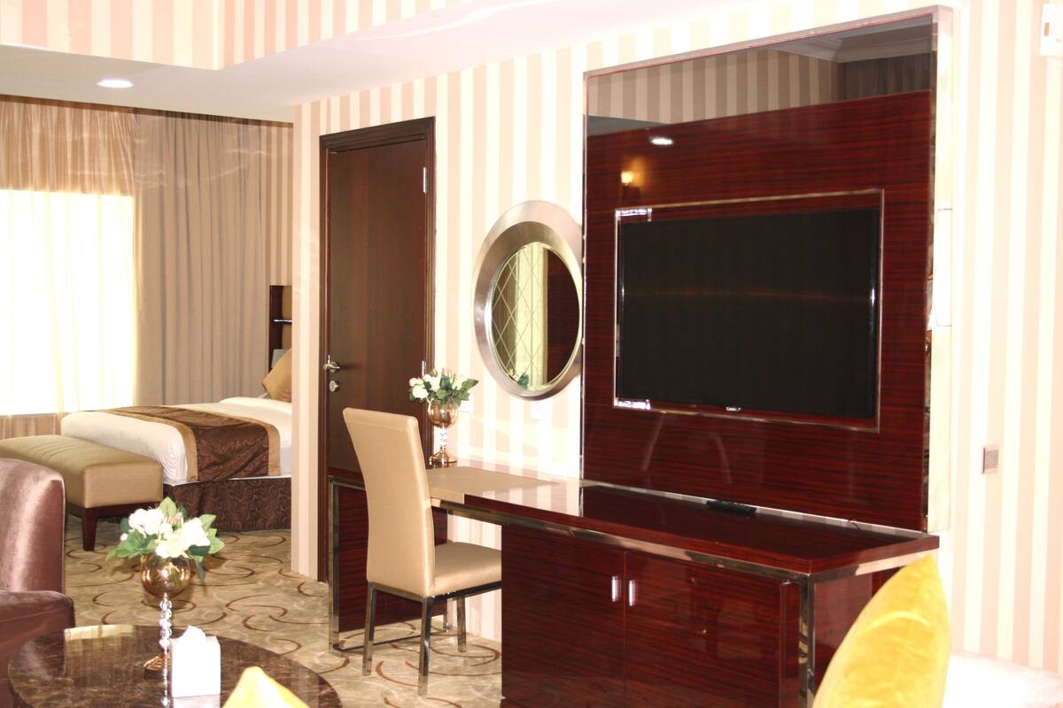 Une chambre d’hôtel avec un lit, un bureau, une chaise, une télévision et un miroir.
