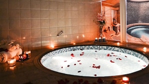 Un espace spa avec un jacuzzi entouré de bougies et de pétales de roses.