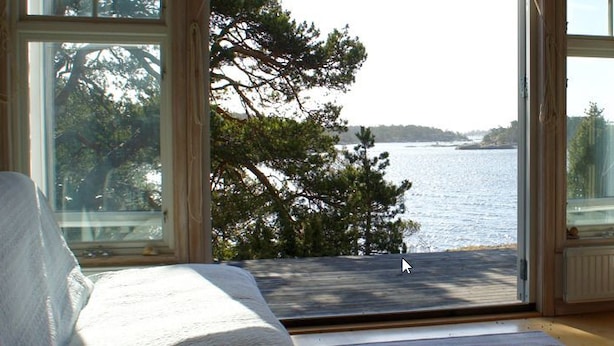 Et værelse med udsigt til en sø, en seng, et bord med et glas og en pejs.