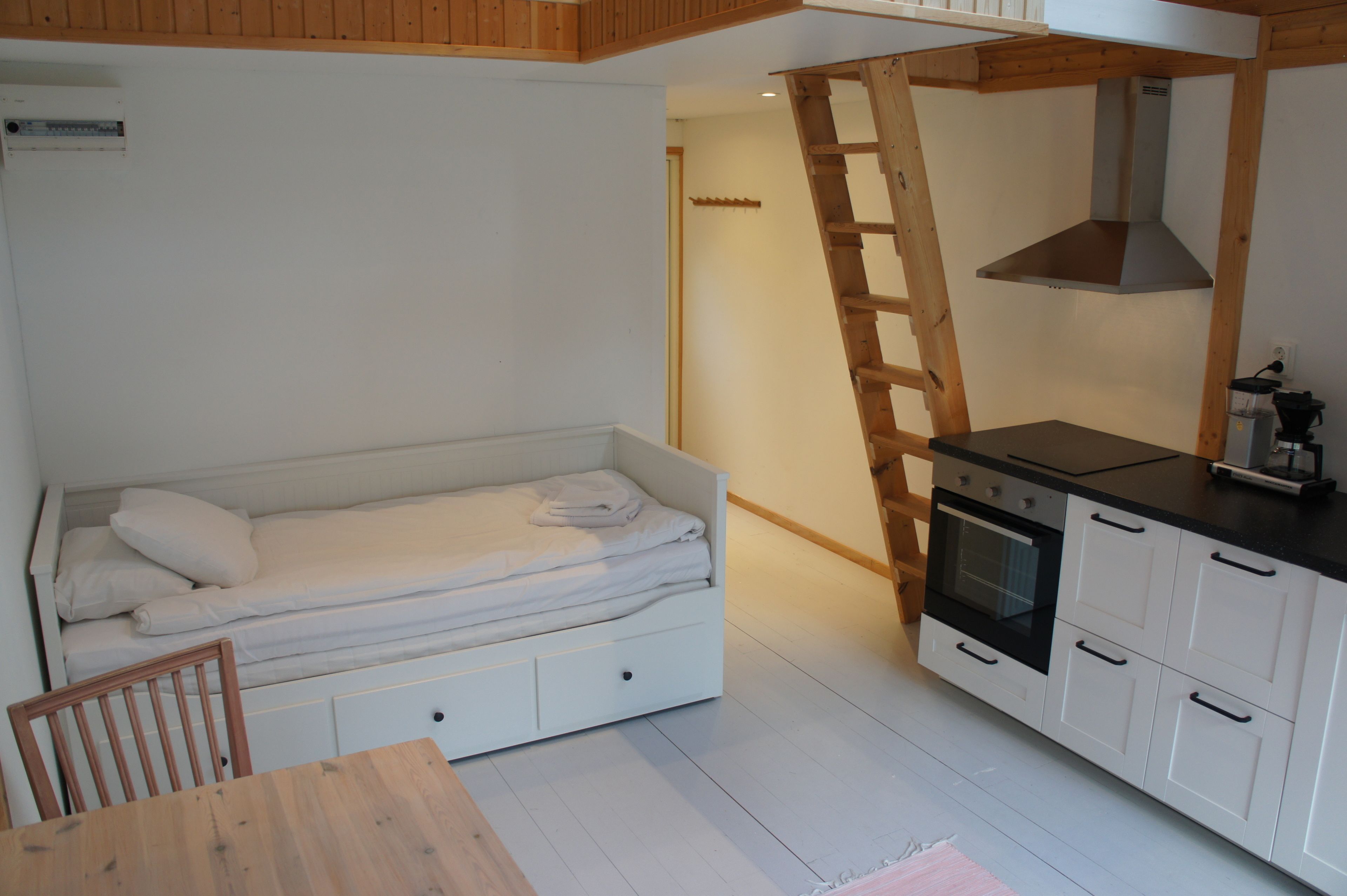 A compact room with a bed, a kitchenette, and a dining area.