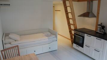 A compact room with a bed, a kitchenette, and a dining area.