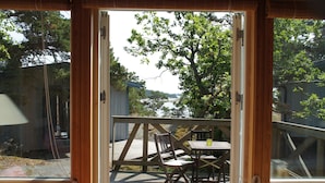 En træterrasse med bord og stole, der vender ud mod vand og træer.