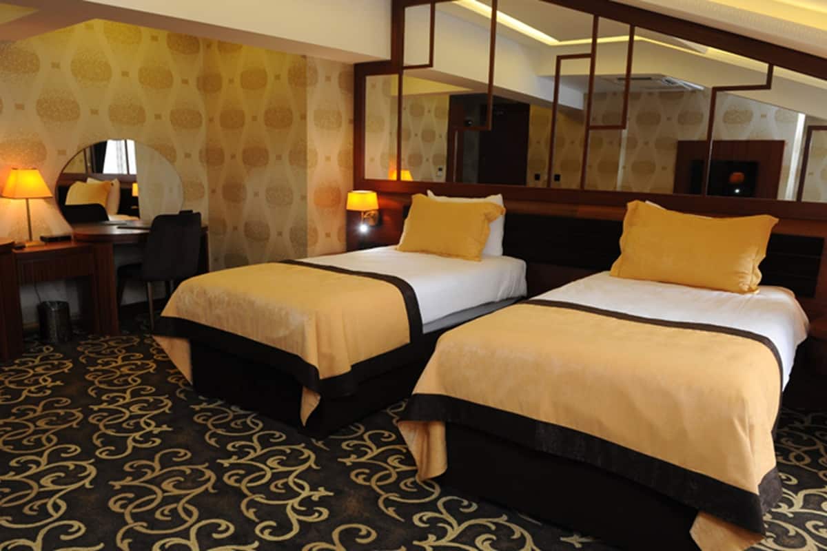 A hotel room with two beds, a desk, and a chair.