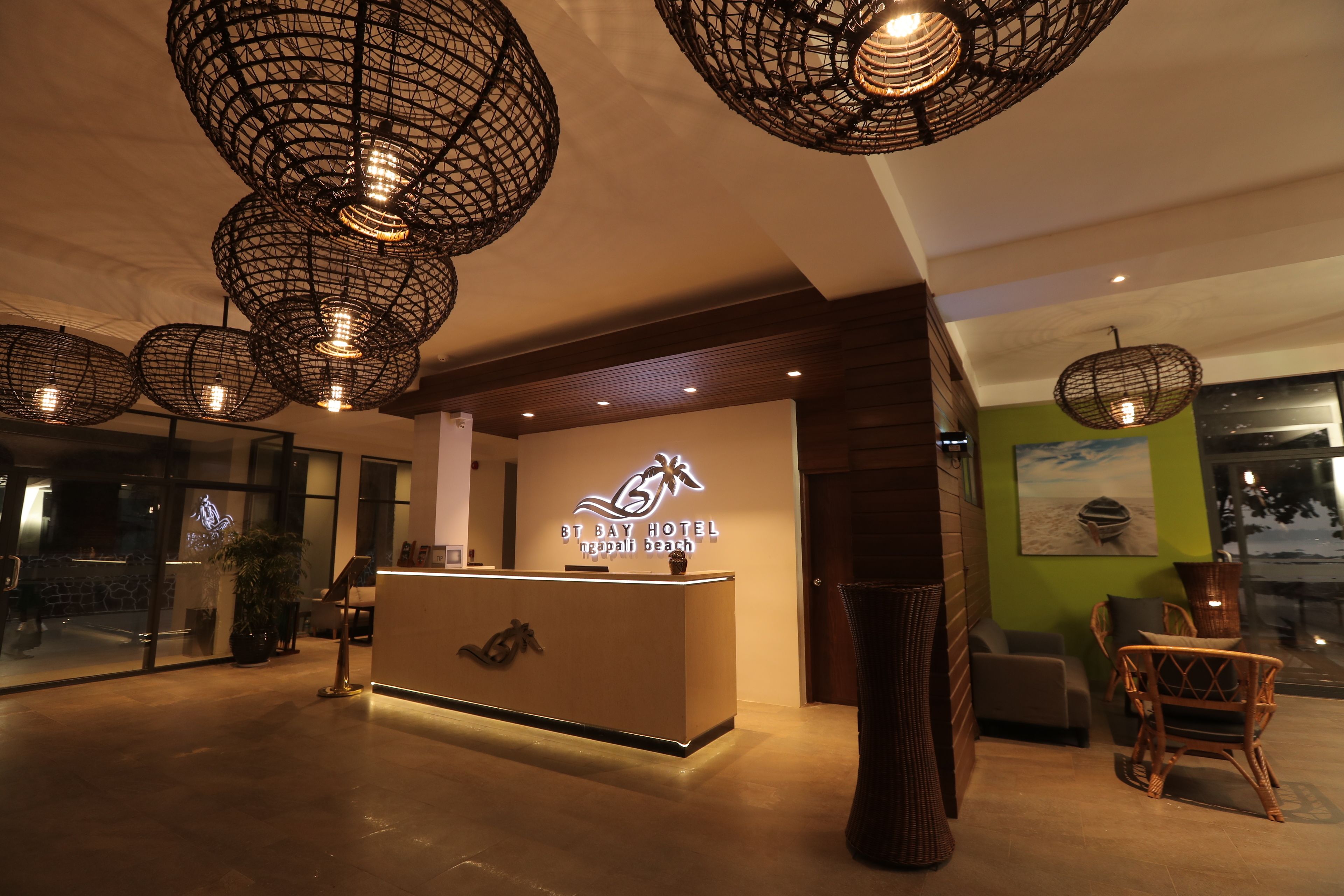 A hotel reception area with a modern design, featuring a reception desk, wicker chairs, and unique hanging light fixtures.