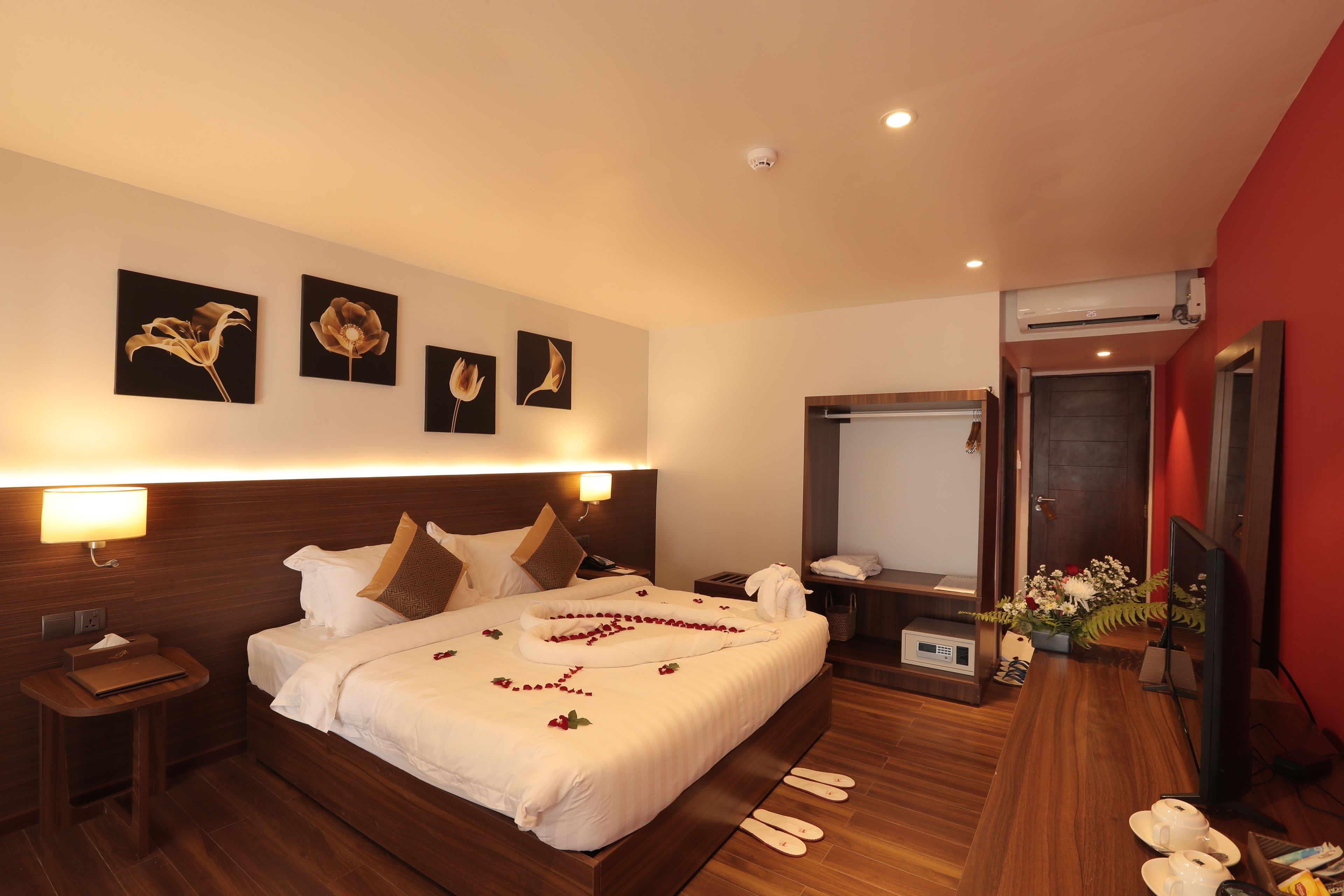 A hotel room with a large bed, a bedside table, a TV, and a mirror.