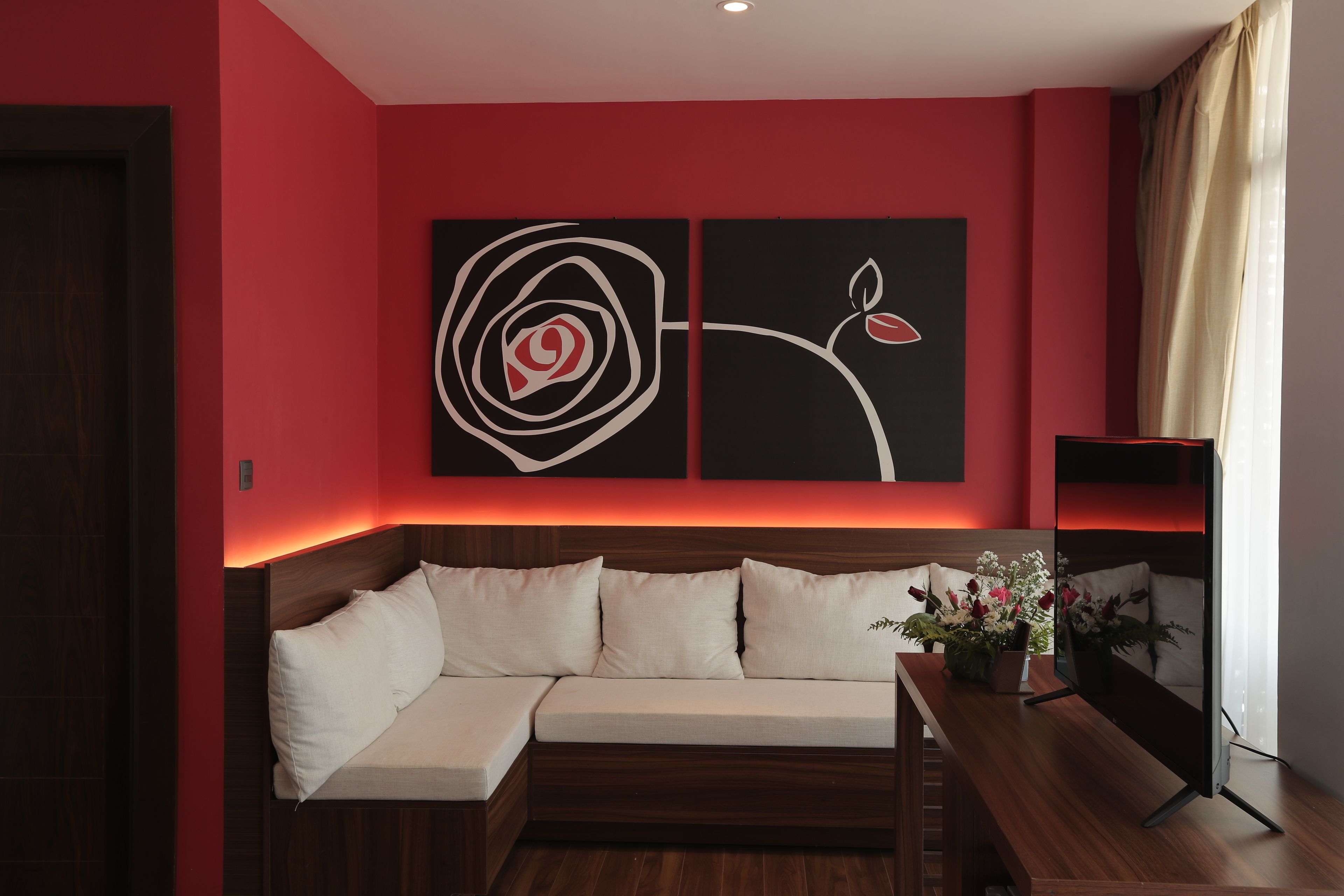 Une chambre moderne avec un canapé doté d’une tête de lit en bois, un téléviseur à écran plat et un grand tableau abstrait accroché au mur.