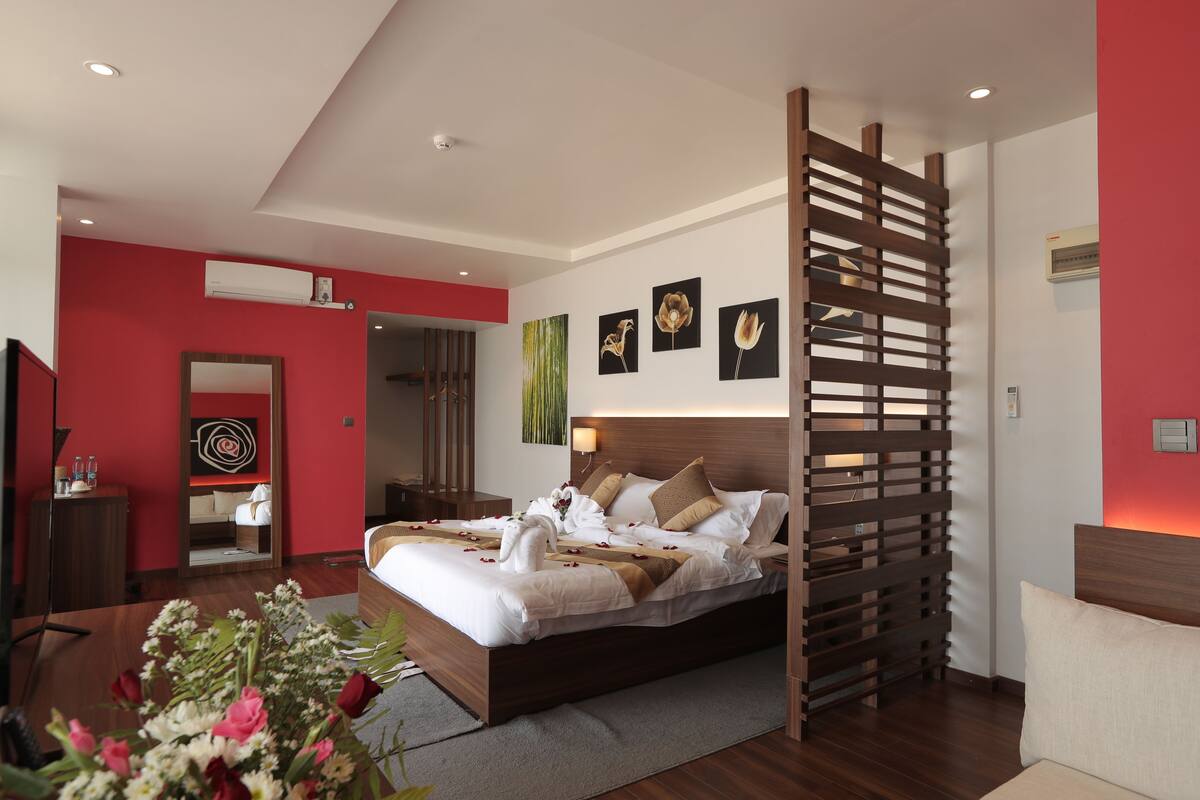 Quarto de hotel moderno com uma cama grande, cabeceira de madeira e um painel decorativo.