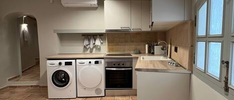 A compact kitchen with a washing machine, oven, and sink.