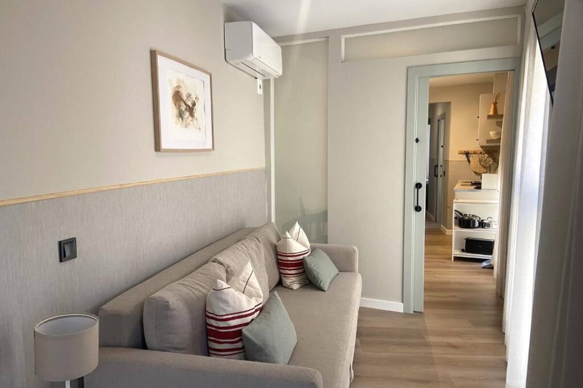 Ein modernes Wohnzimmer mit einer Couch, Kissen, einer Lampe und einem gerahmten Bild an der Wand.