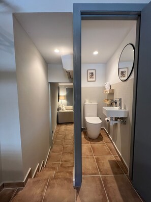 Un baño moderno con inodoro, lavabo y zona de ducha.